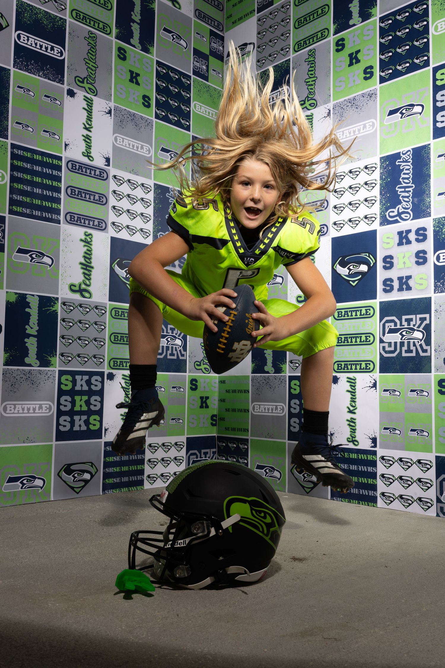 Dynamic studio photoshoot with vibrant Seattle Seahawks themed backdrop and lighting.