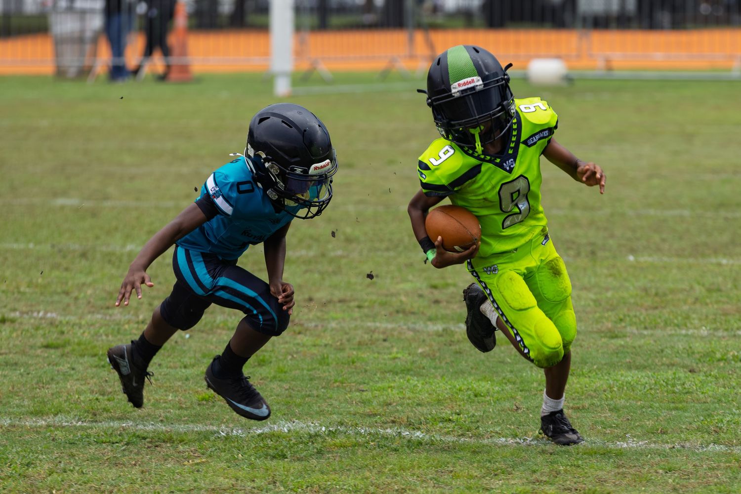 Players in neon green and teal uniforms competing during a youth football game.