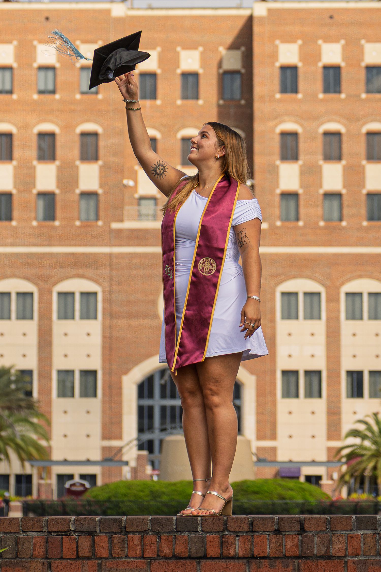 Celebratory graduation photoshoot on brick wall at Florida State University campus.