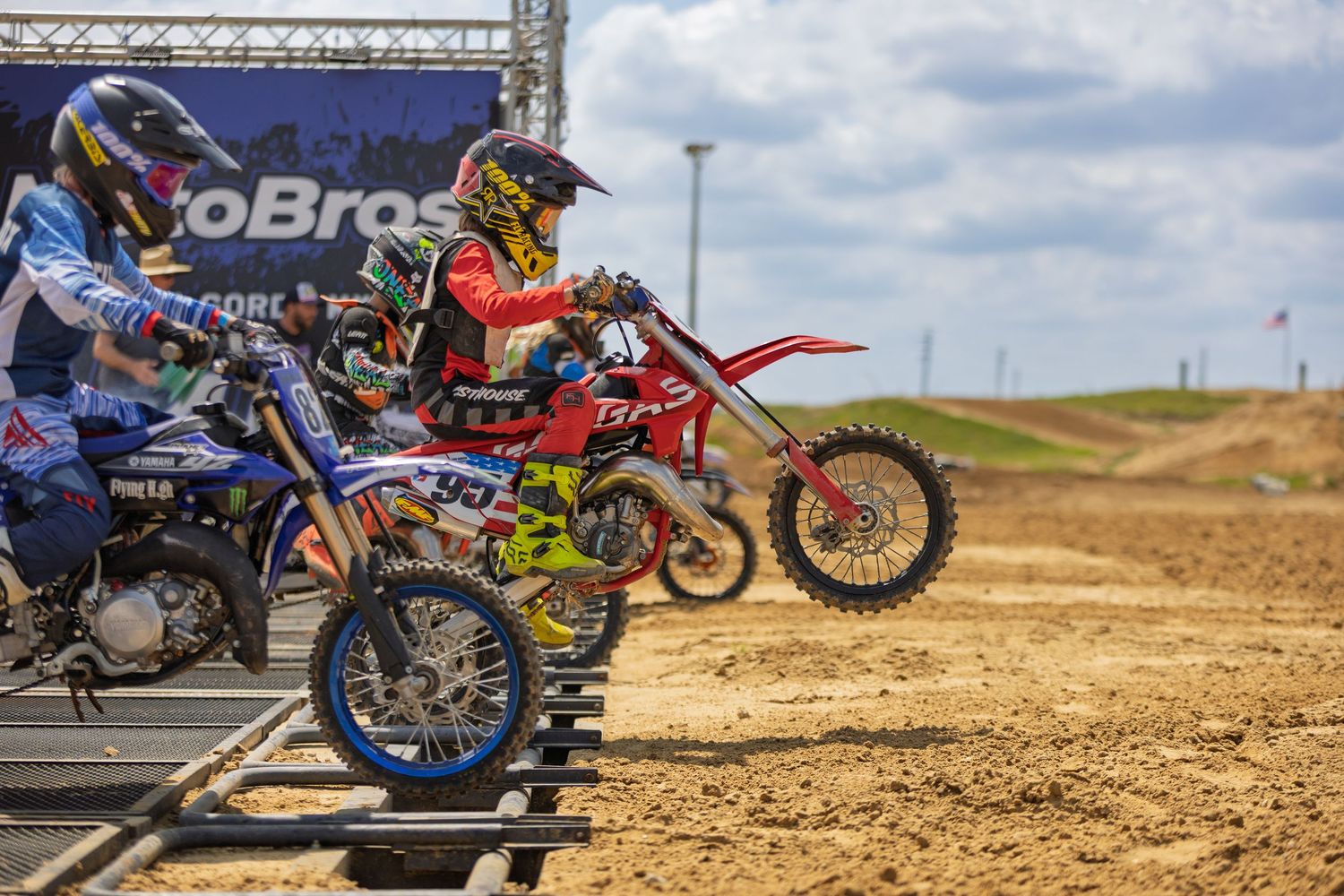 Row of motocross bikes lined up at an outdoor dirt track competition.