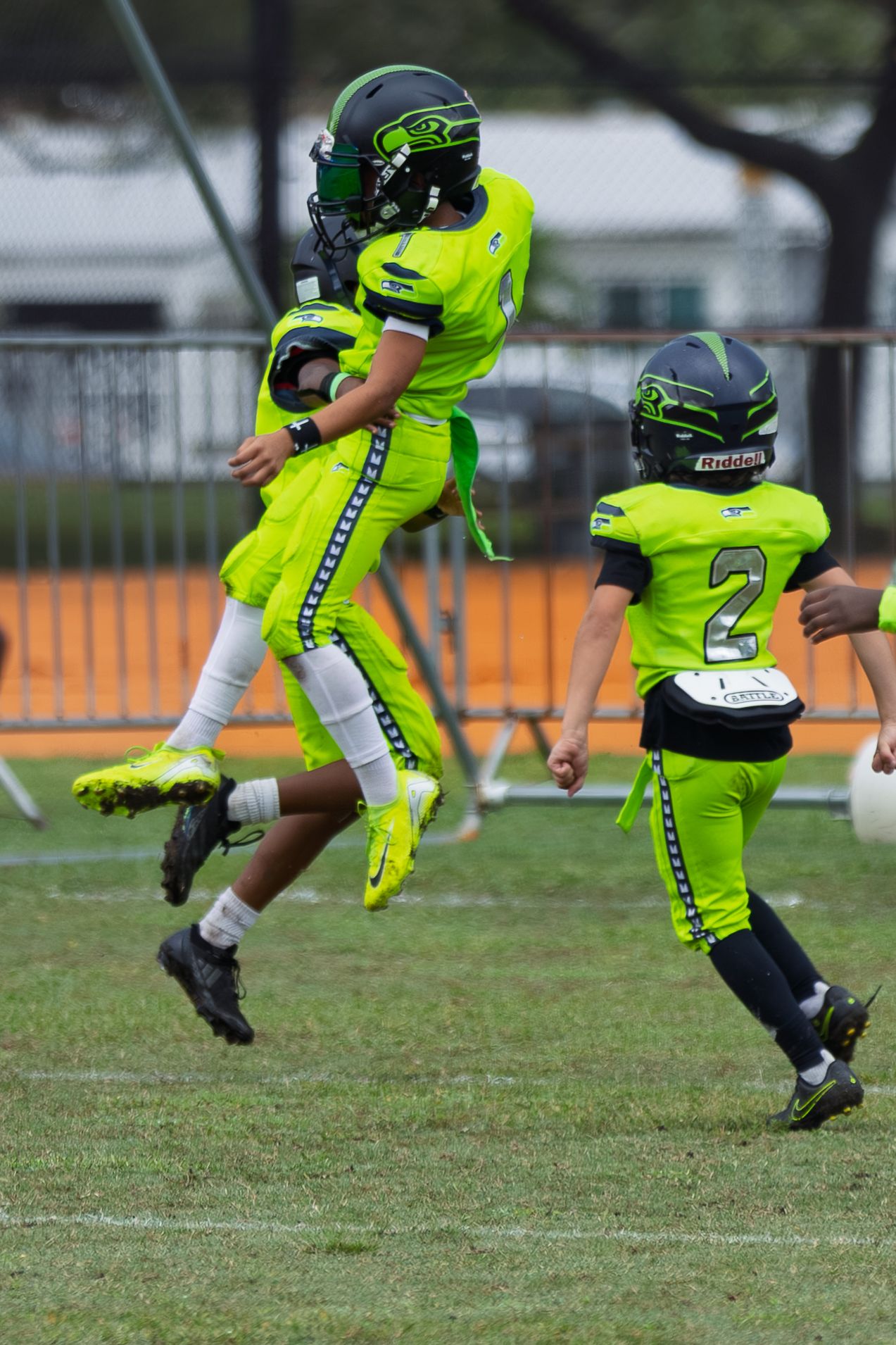 Close-up sequence of neon green football cleats and uniforms in action on a grass field.