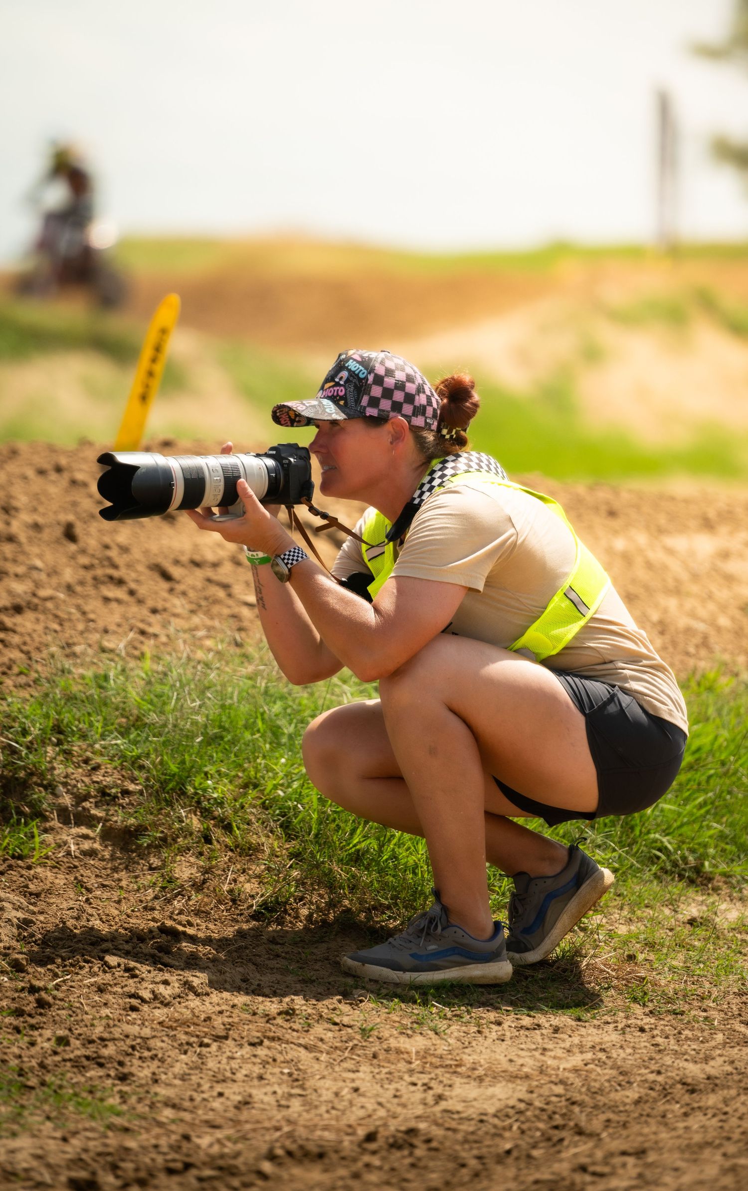 Photographer crouches low to capture action shots at outdoor sports event.