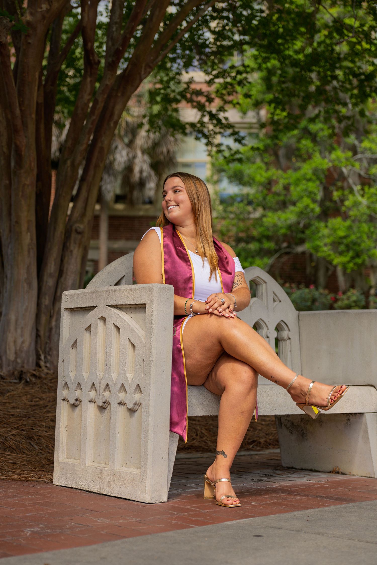A woman in pink sitting on a white bench in a garden setting.