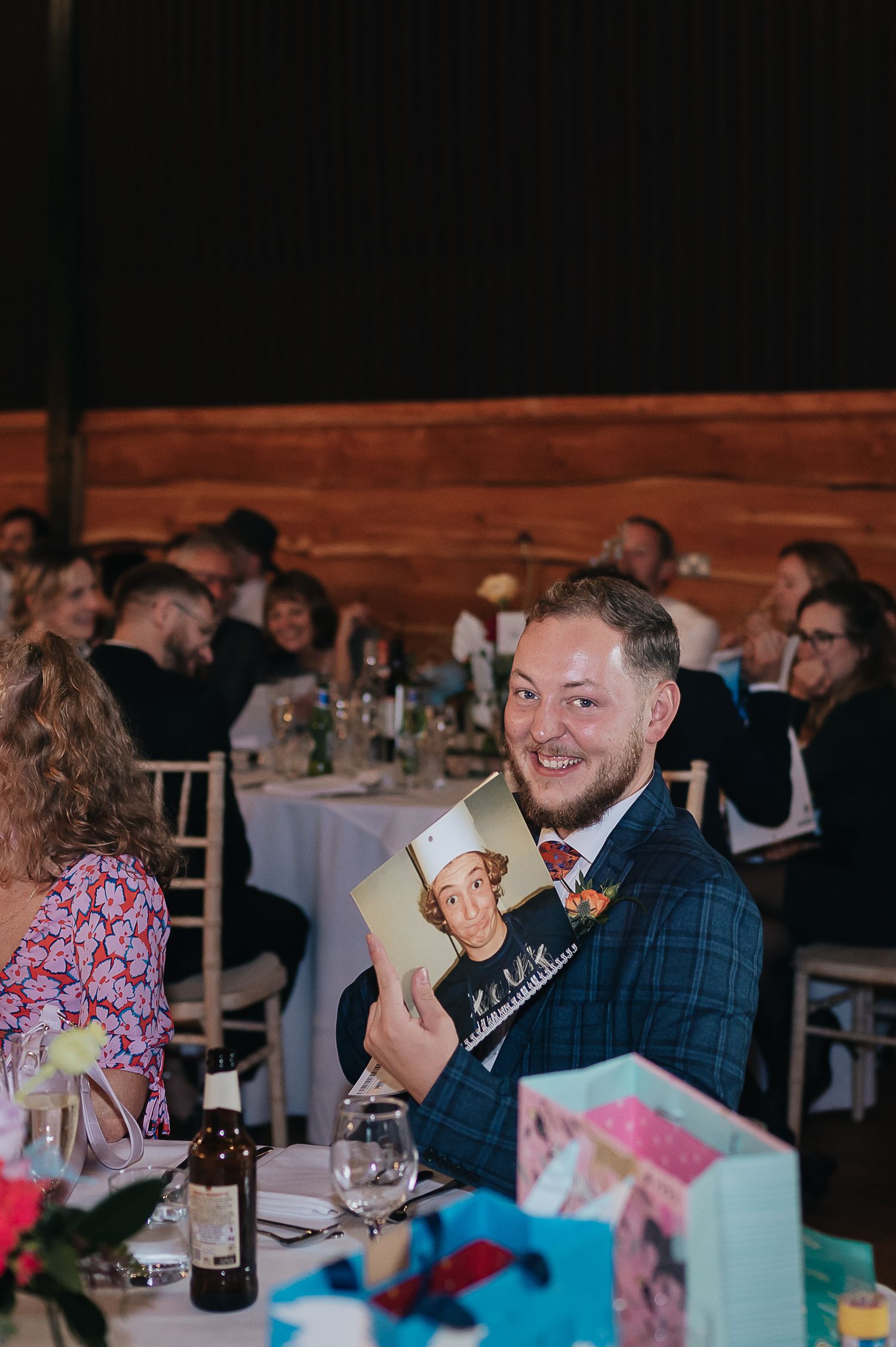 A wedding guest smiling while holding up a card during the reception dinner.