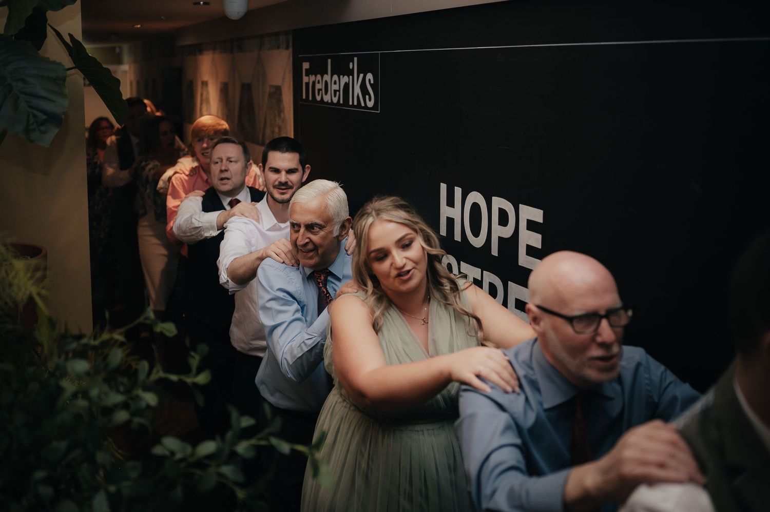 Wedding guests form a conga line during reception party festivities.