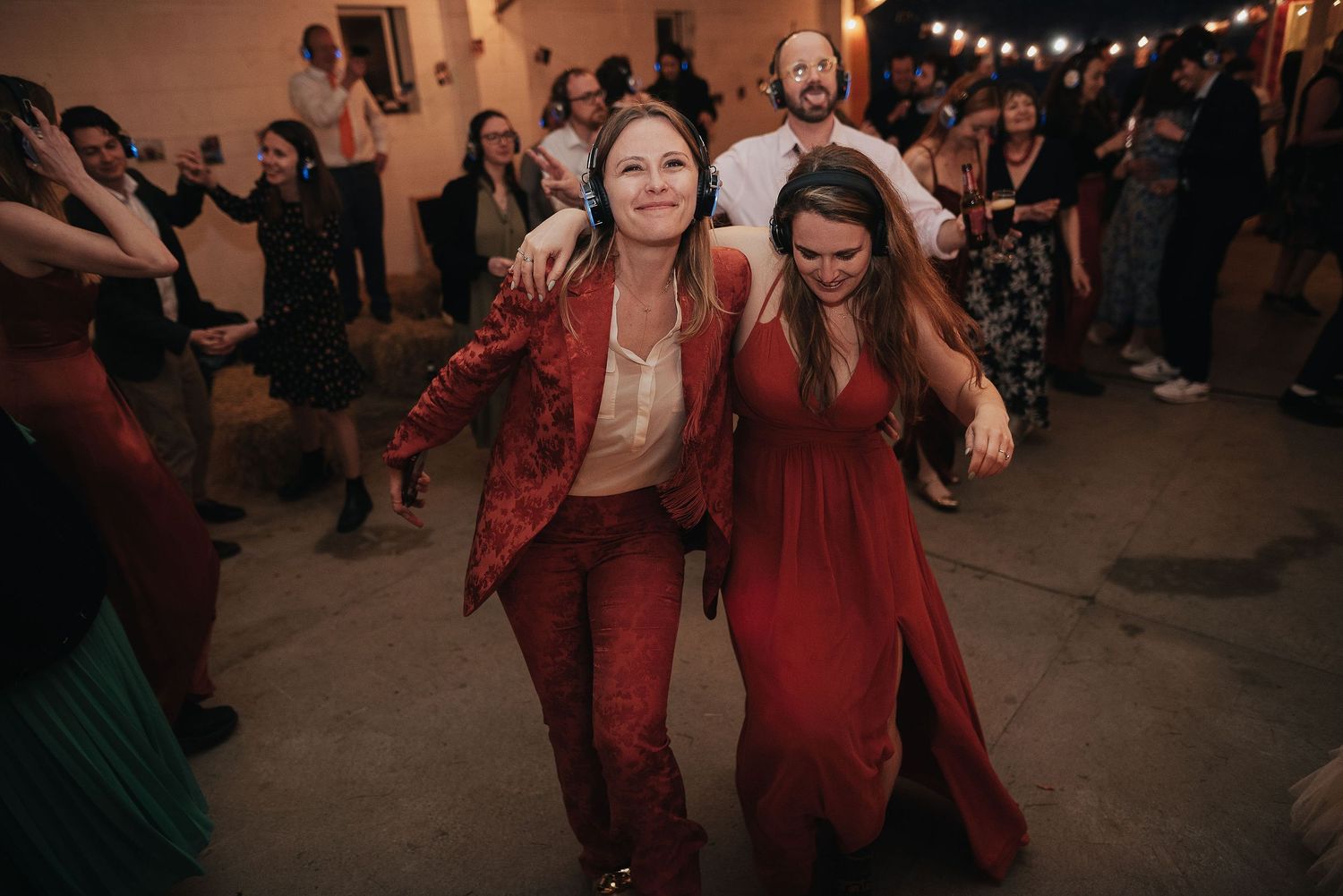 Two guests in matching red outfits dance exuberantly at a wedding celebration.