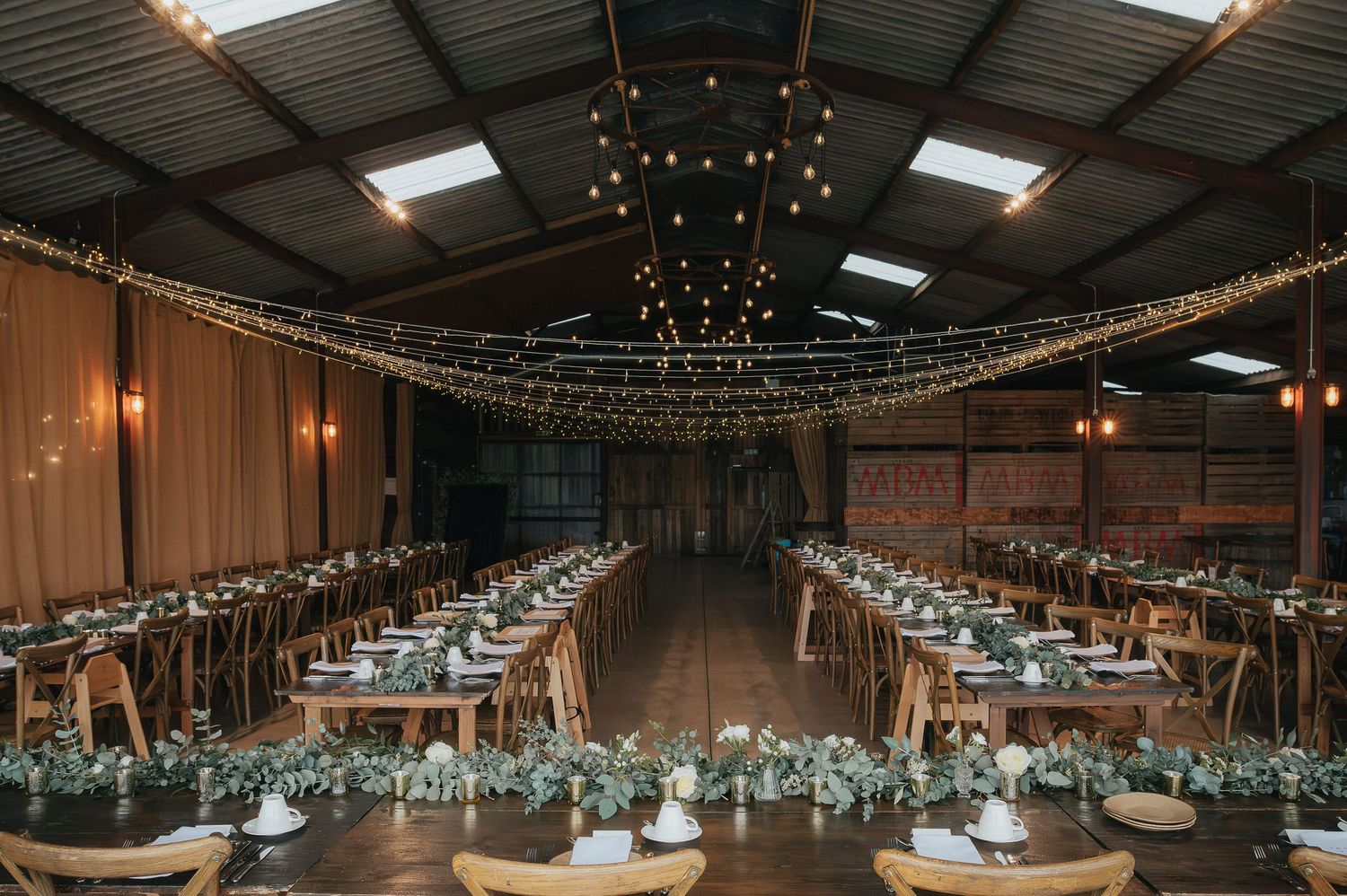 Rustic barn wedding reception setup with string lights and long tables.