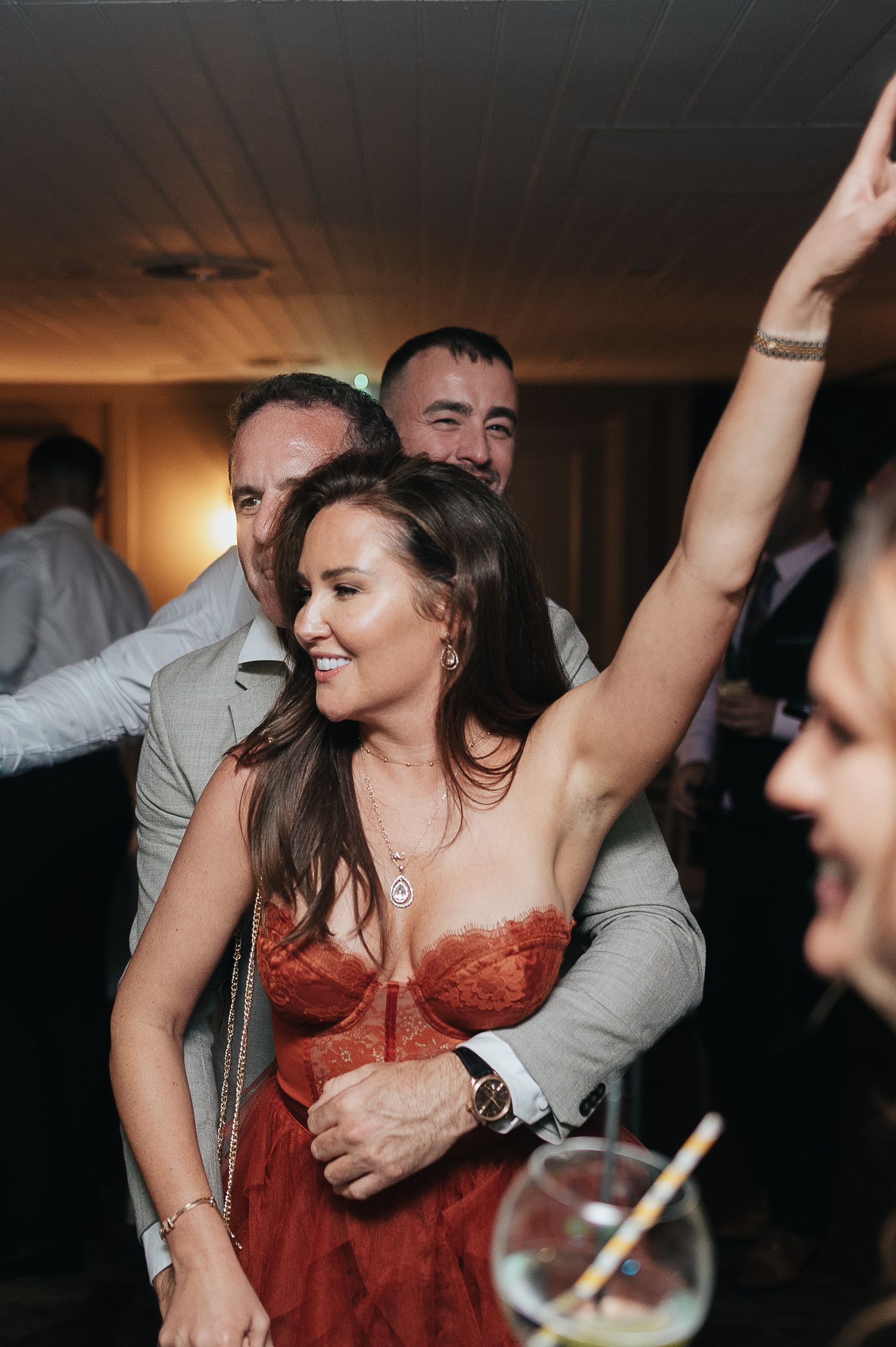 People dancing and celebrating with drinks in hand at a lively indoor party.
