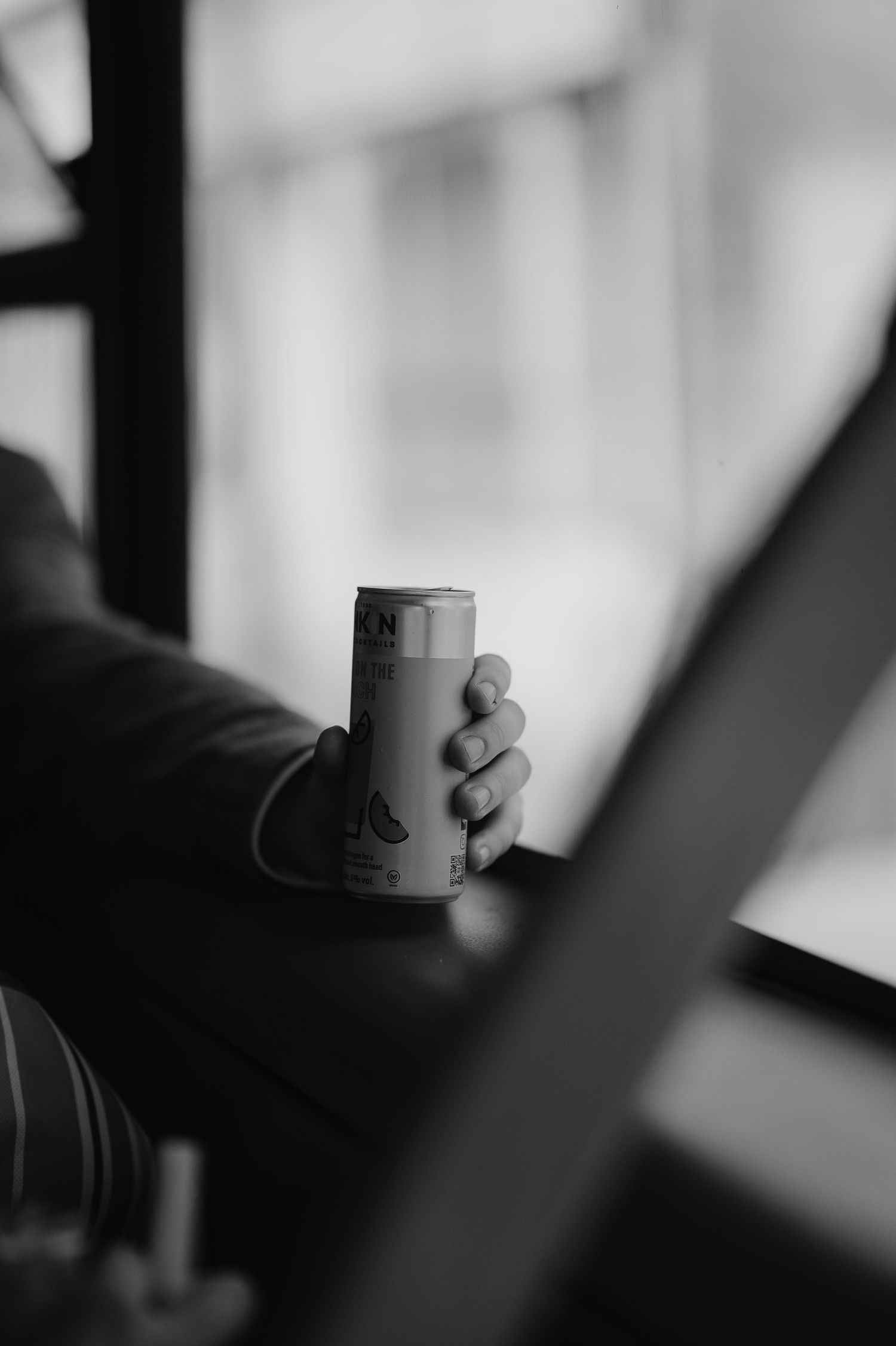 A hand holding a beverage can in black and white photography.