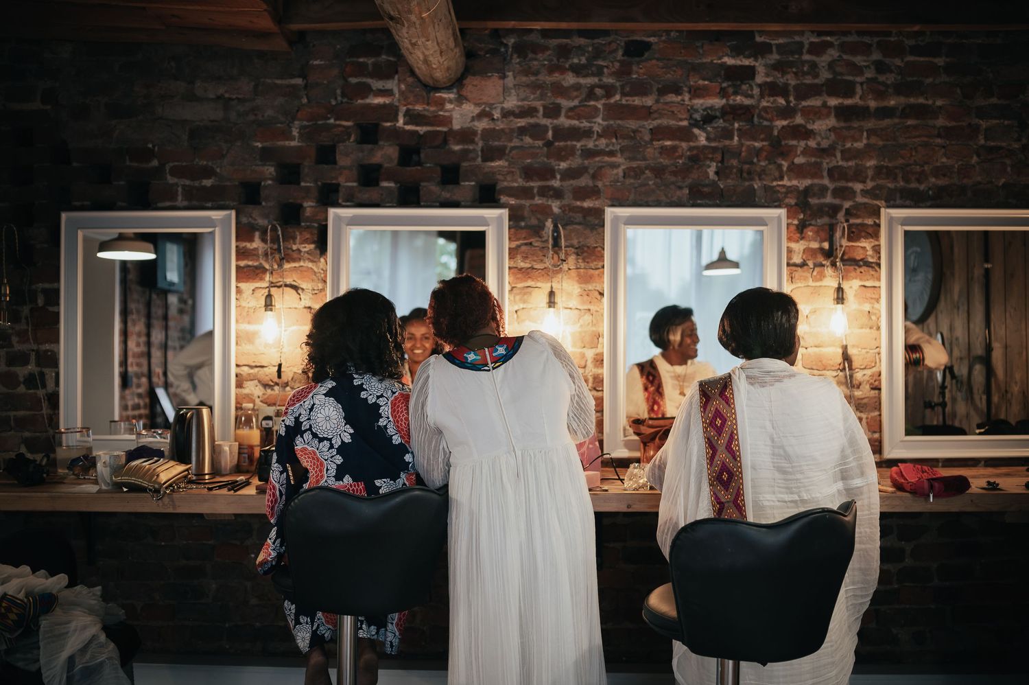 Wedding dress preparation scene in rustic brick room with warm lighting.