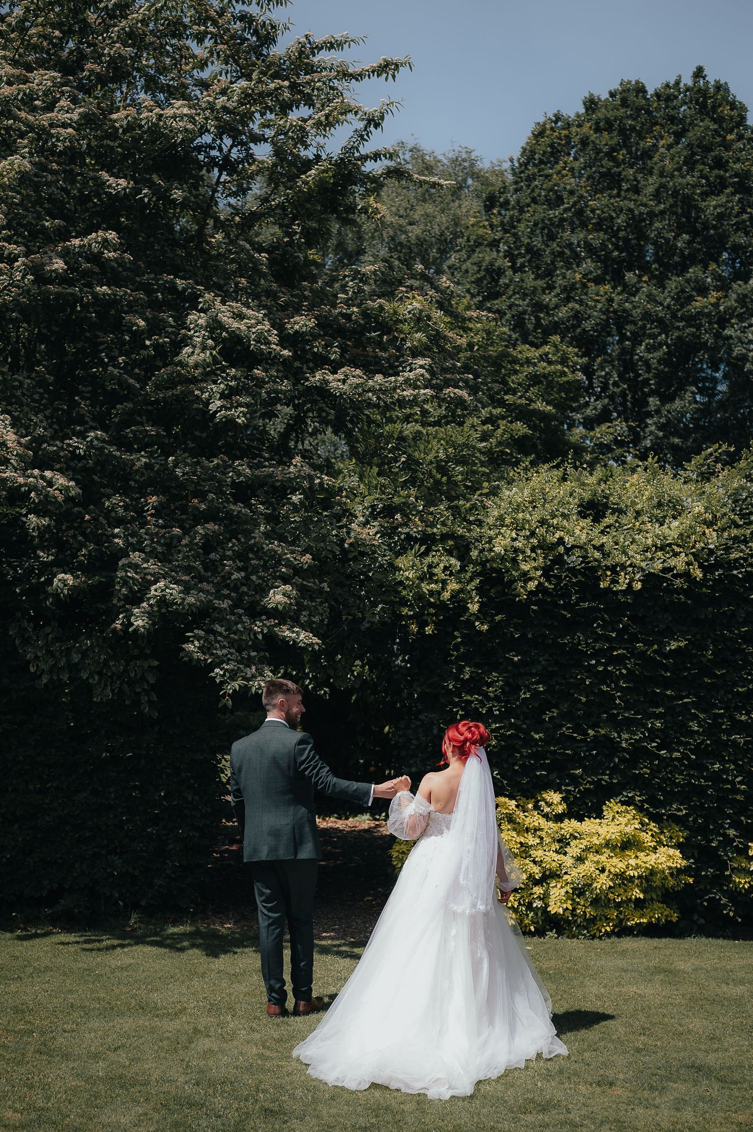 A wedding couple shares an intimate moment in a garden setting surrounded by lush greenery.