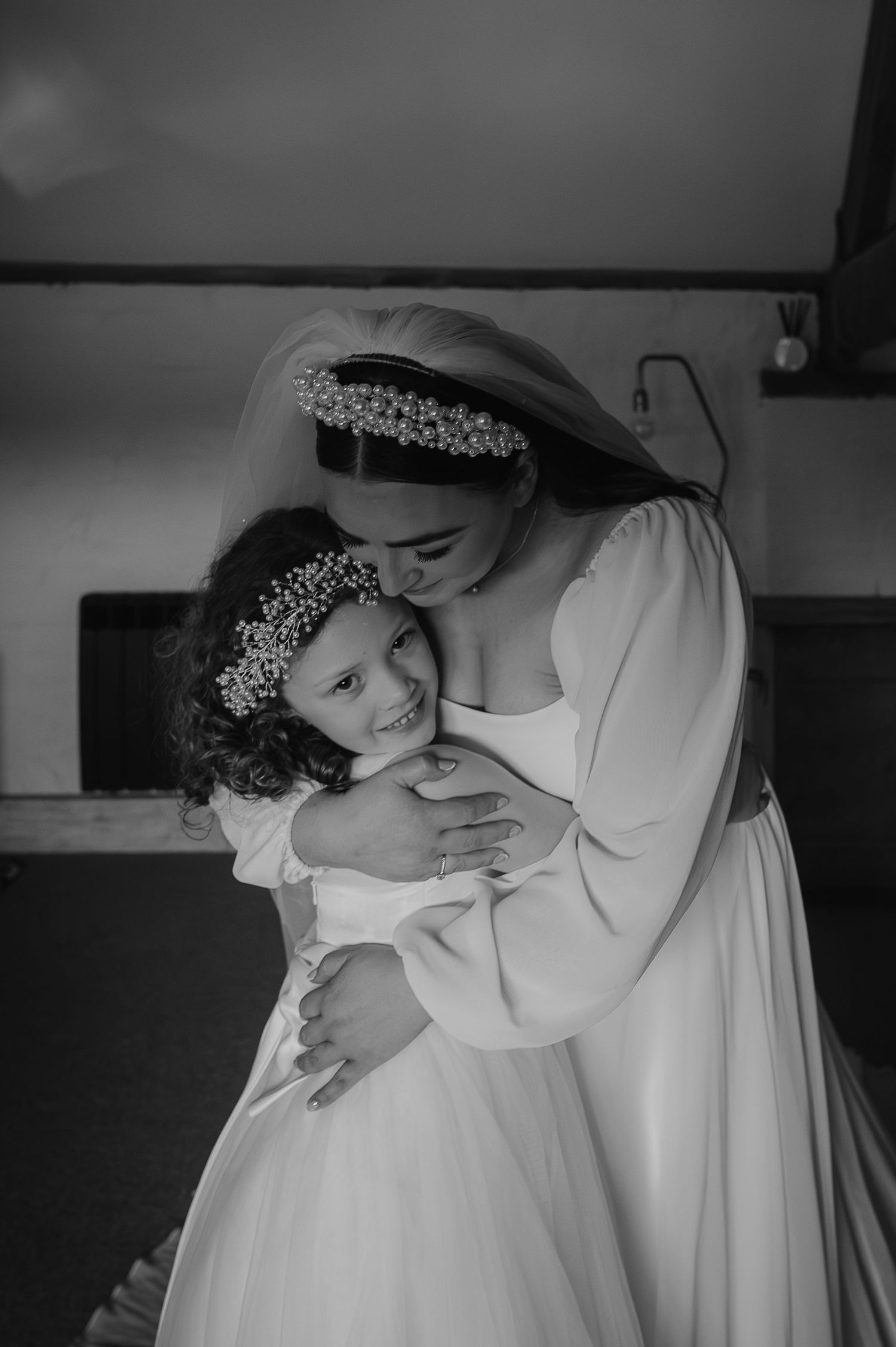 A tender embrace between two people wearing white dresses and floral crowns.