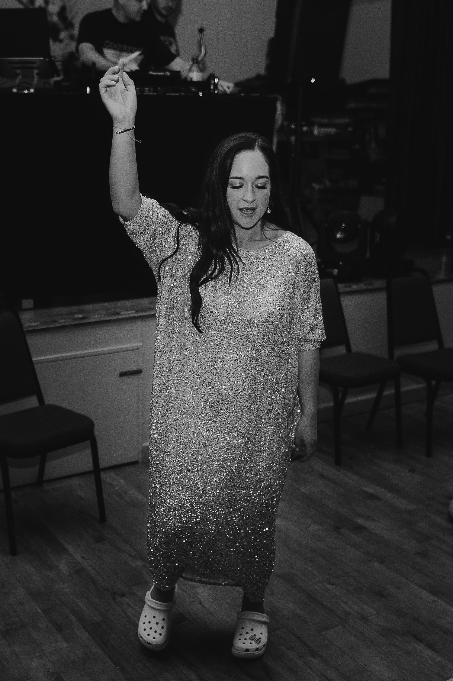 A dancer in a sparkly dress strikes a pose on a wooden floor.