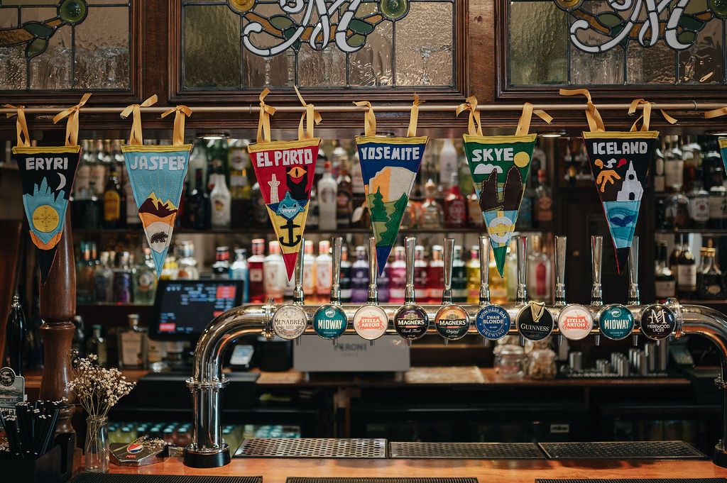 Vintage-style bar setup with multiple beer taps and colorful draft handles in a dimly lit setting.