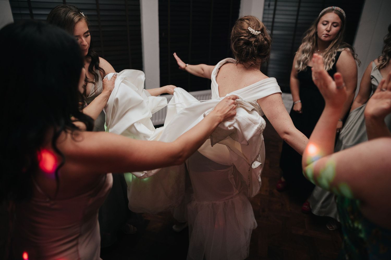 Bridesmaids helping adjust the wedding dress during celebration.