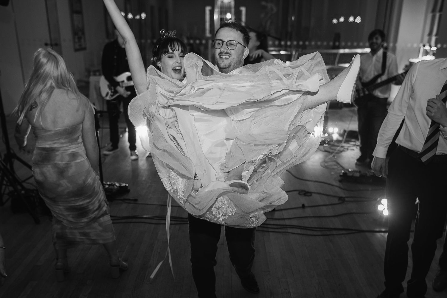 Energetic dance floor moment captured in black and white at a wedding reception.