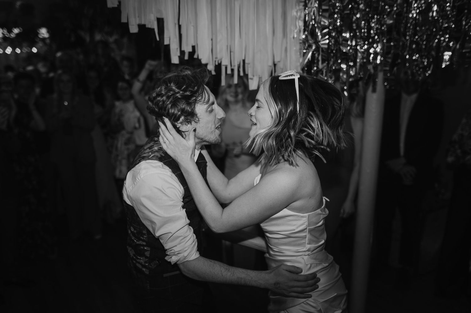 A romantic black and white shot of a couple sharing an intimate dance moment at an evening celebration.