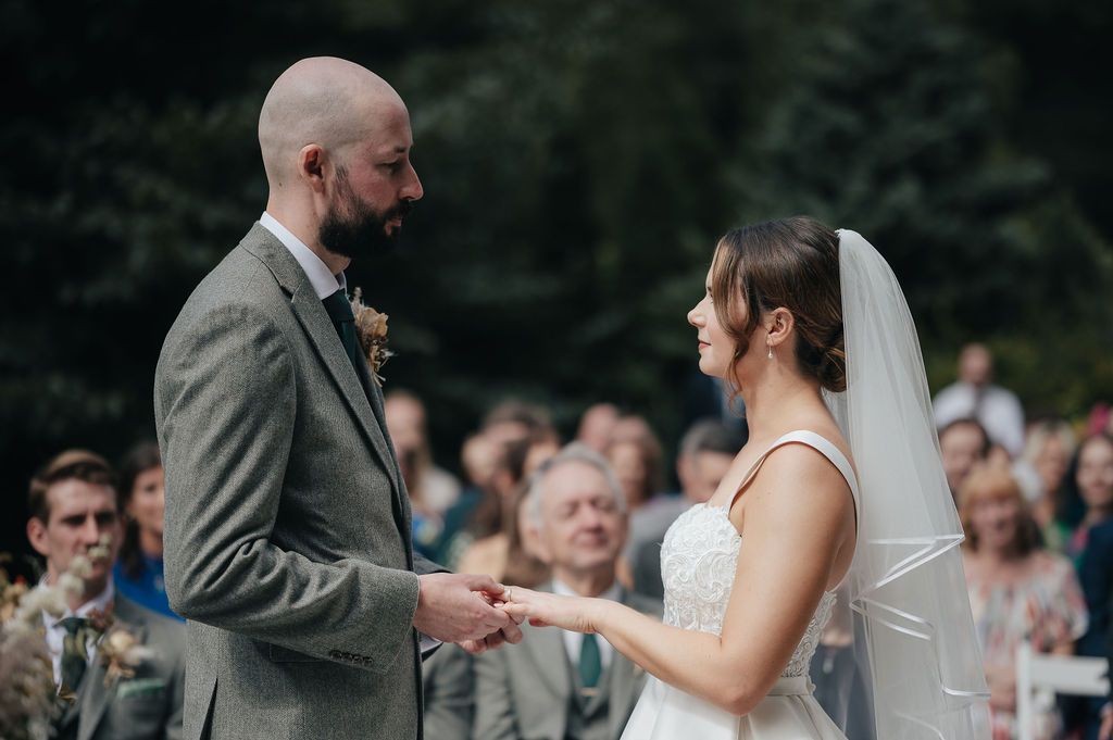 An intimate outdoor wedding ceremony showing the exchange of rings between a couple.