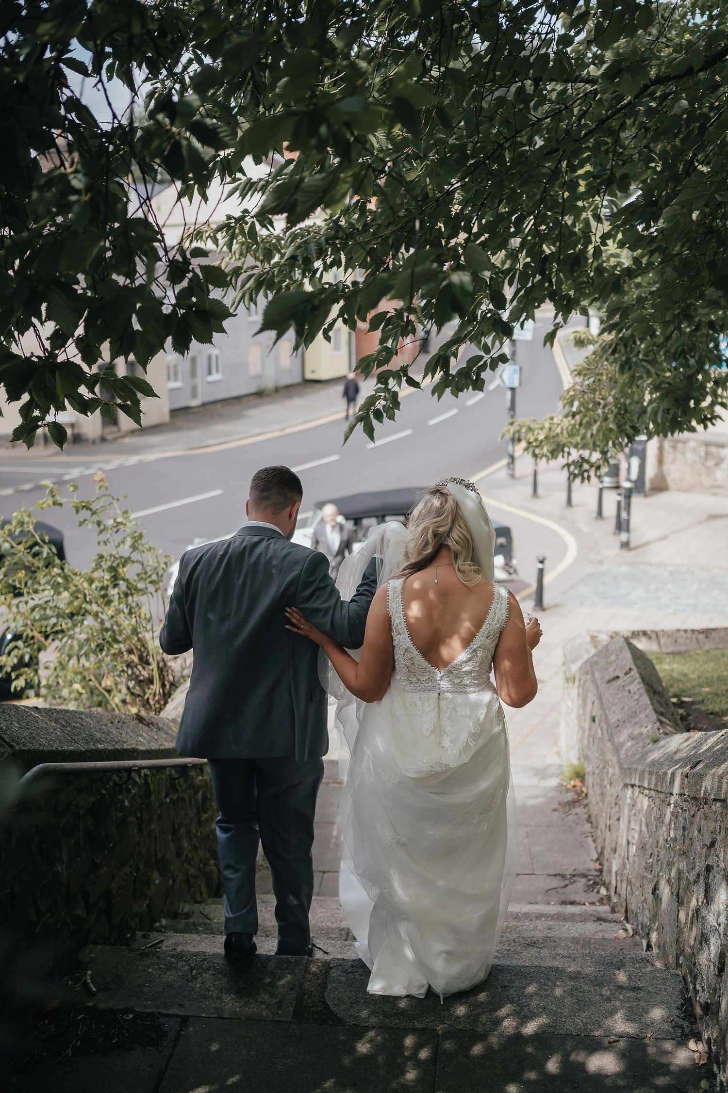 Wedding couple walking down stone steps together while holding drinks in their hands.