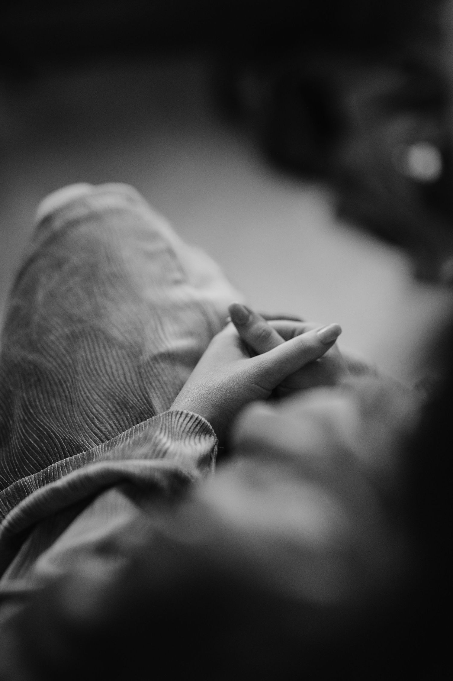 Artistic black and white close-up of hands resting gently on denim fabric.