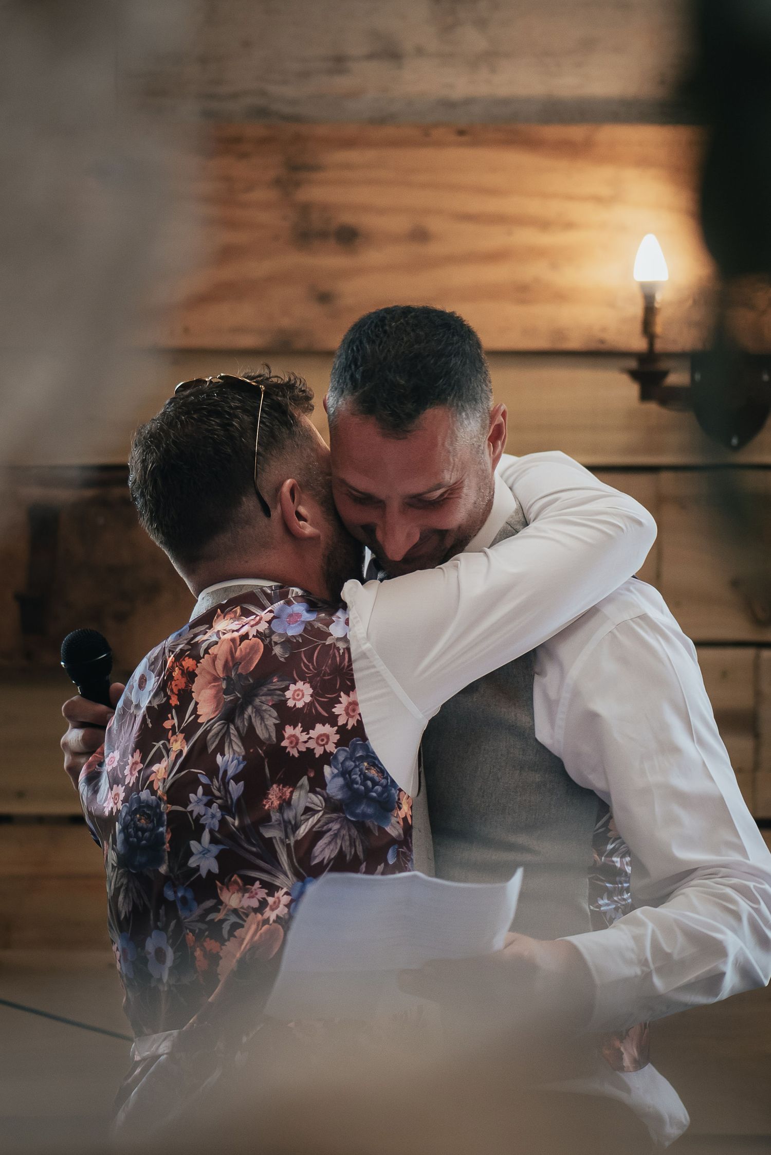 Intimate wedding couple sharing a tender moment in a rustic wooden interior with warm lighting.
