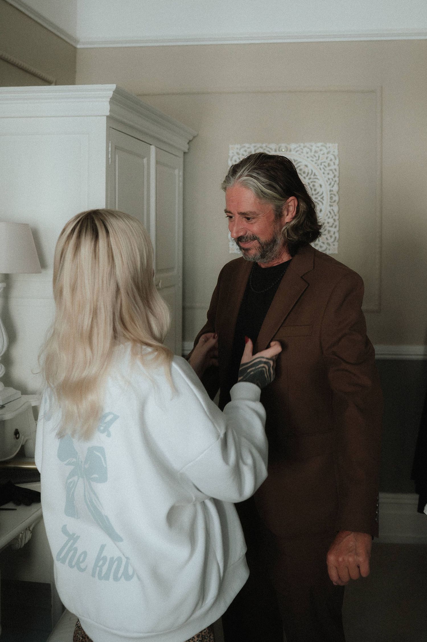 Two people having an animated conversation in a white interior room.