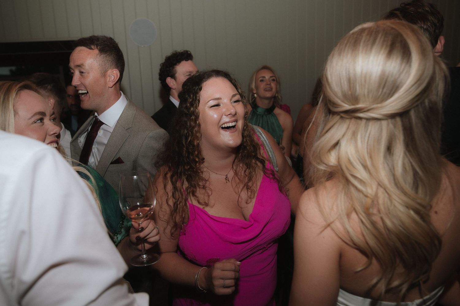 Wedding reception party with guests dancing and celebrating in colorful attire.