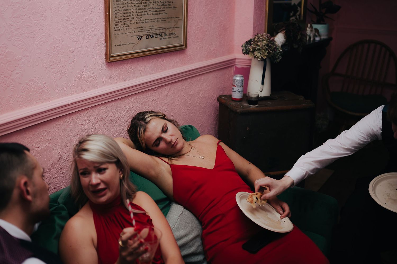 People dancing and laughing together at a party with pink walls in the background.