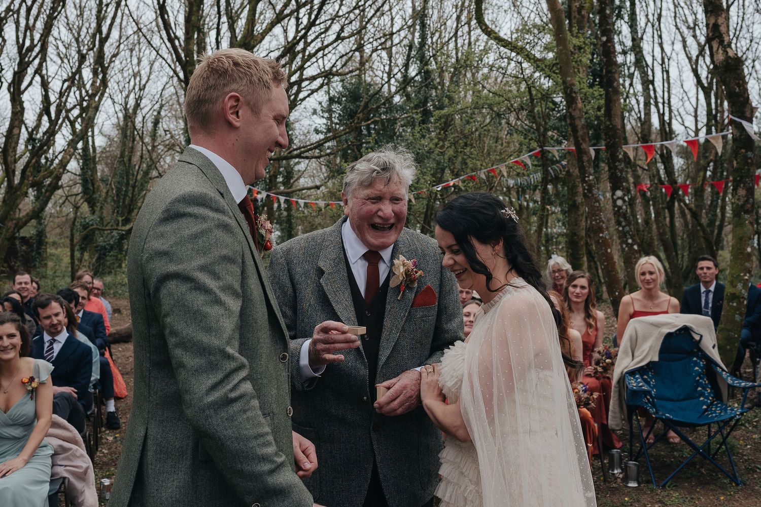 Outdoor wedding ceremony moment in wooded setting with string lights.