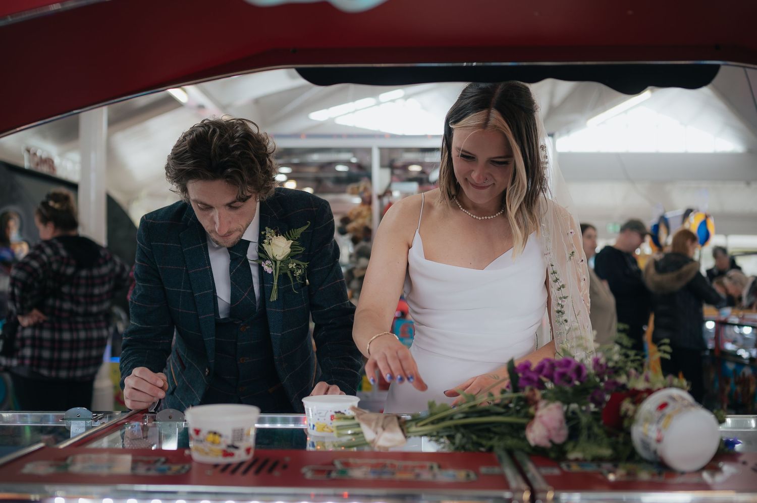 Wedding couple signing documents at an arcade-style counter.
