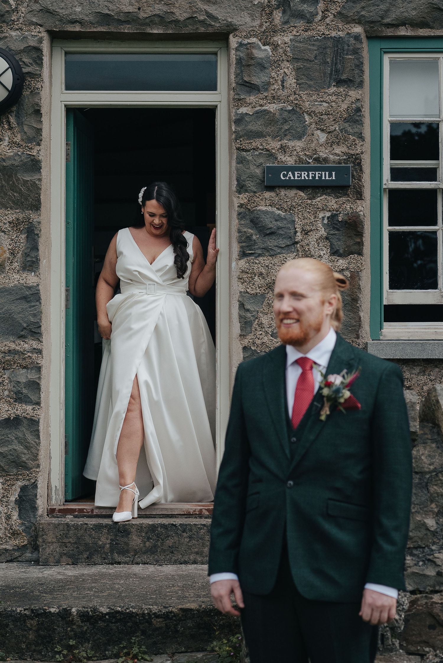 Wedding couple poses at entrance of stone building named Caerfylli with bride in doorway.