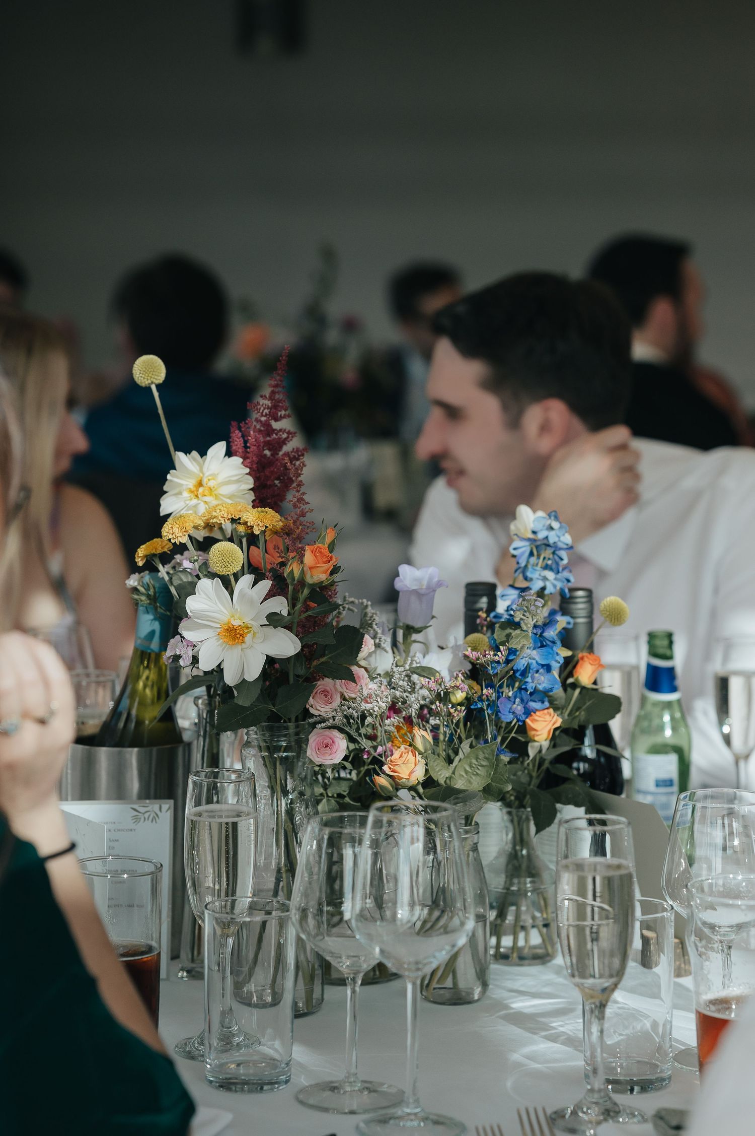 Elegant wedding reception table decorated with colorful wildflower centerpieces and glassware.