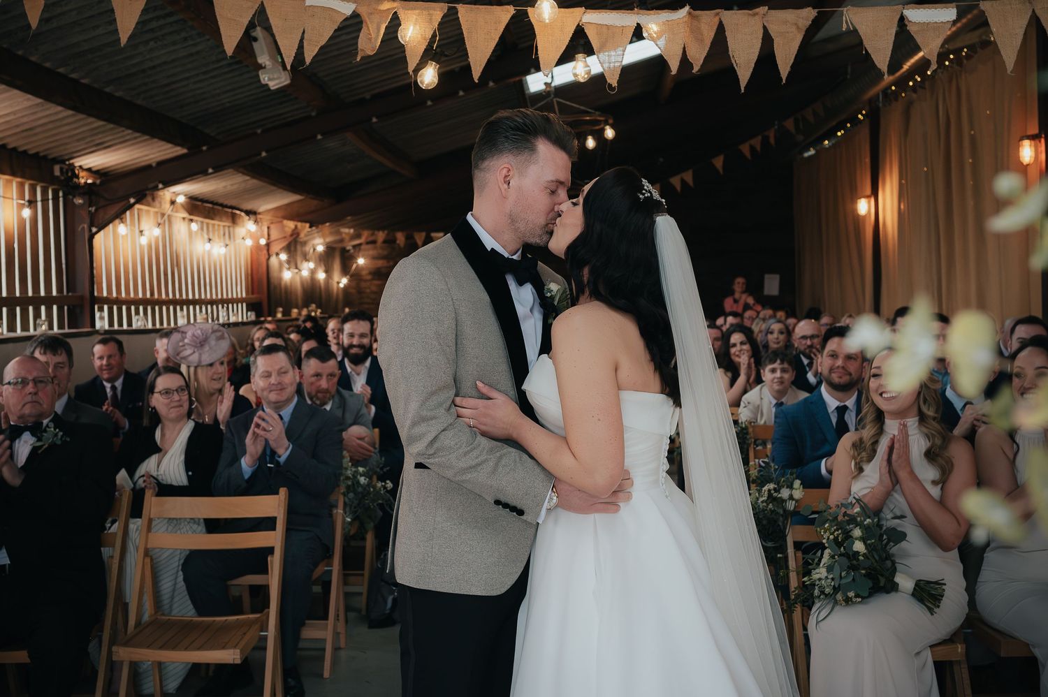 Couple shares intimate moment during reception under string lights and bunting decorations.