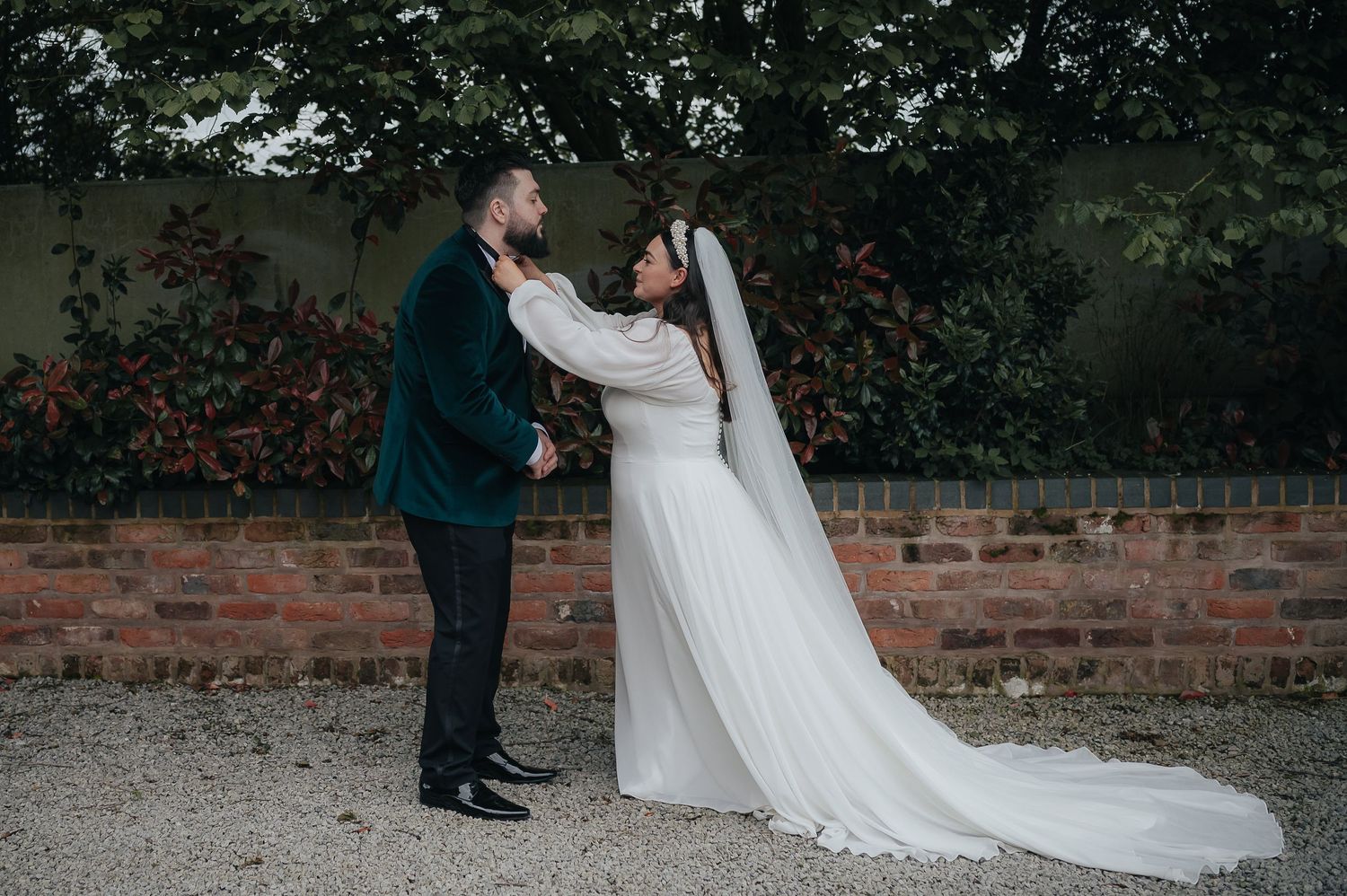 Intimate moment between newlyweds on gravel path with trailing wedding dress.