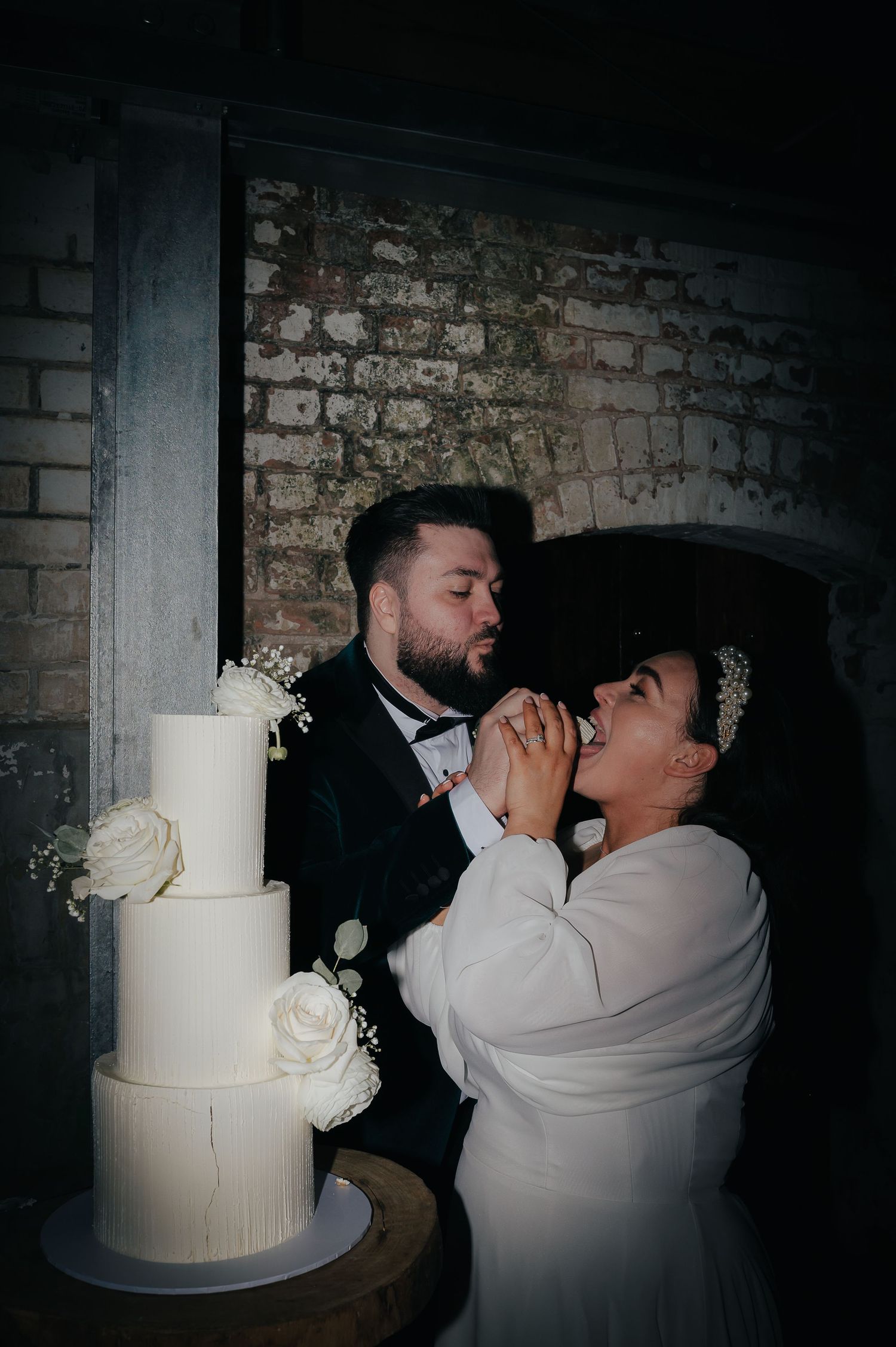 Newlyweds sharing a playful moment while cutting their elegant white wedding cake.