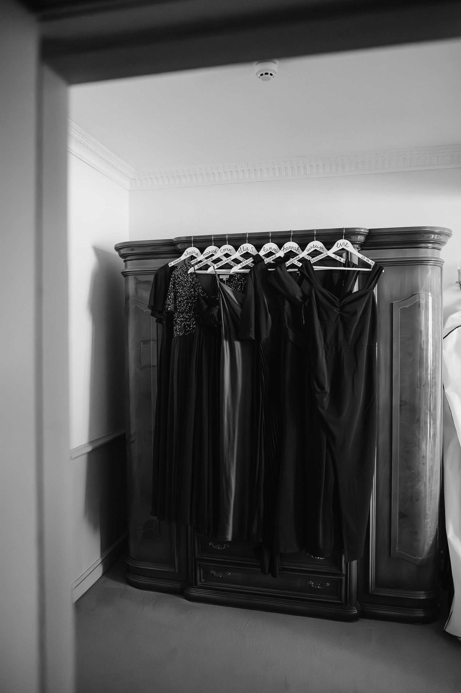 Row of dark formal dresses hanging in a wooden wardrobe.
