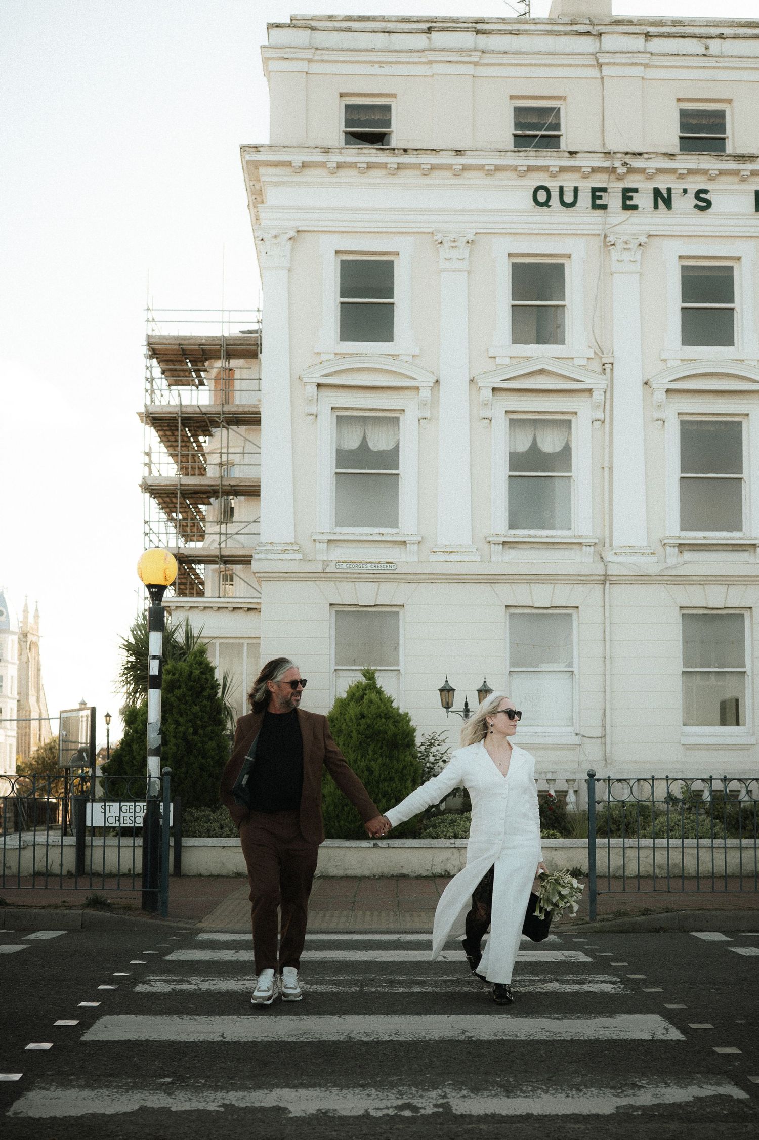 Couple standing in front of white historic Queen's building with classical architecture.