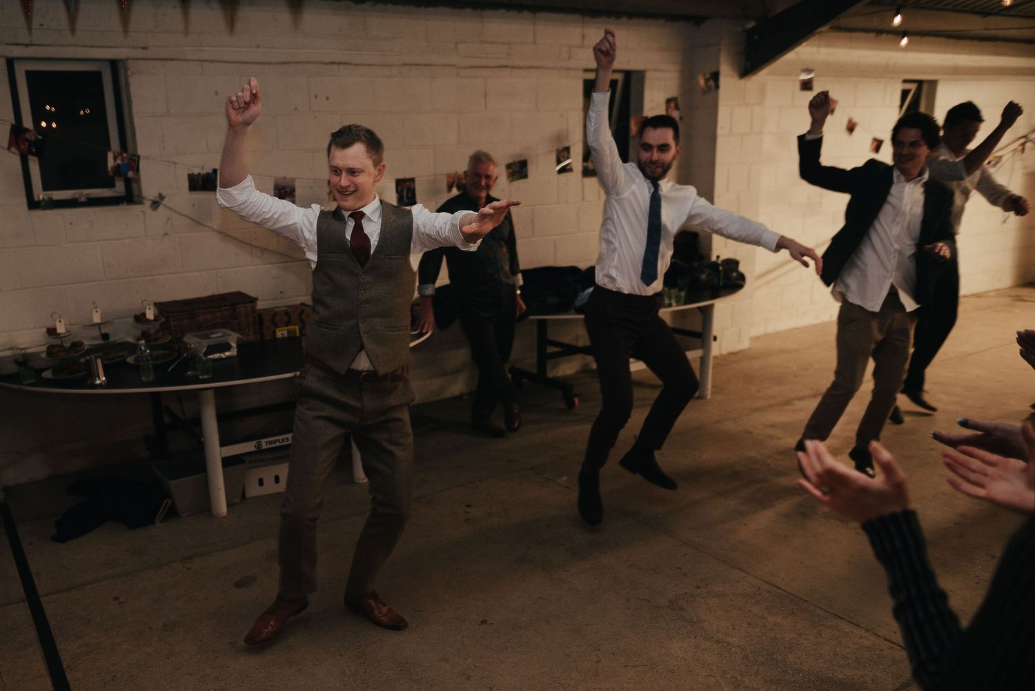 Wedding guests performing synchronized dance moves at an indoor reception.