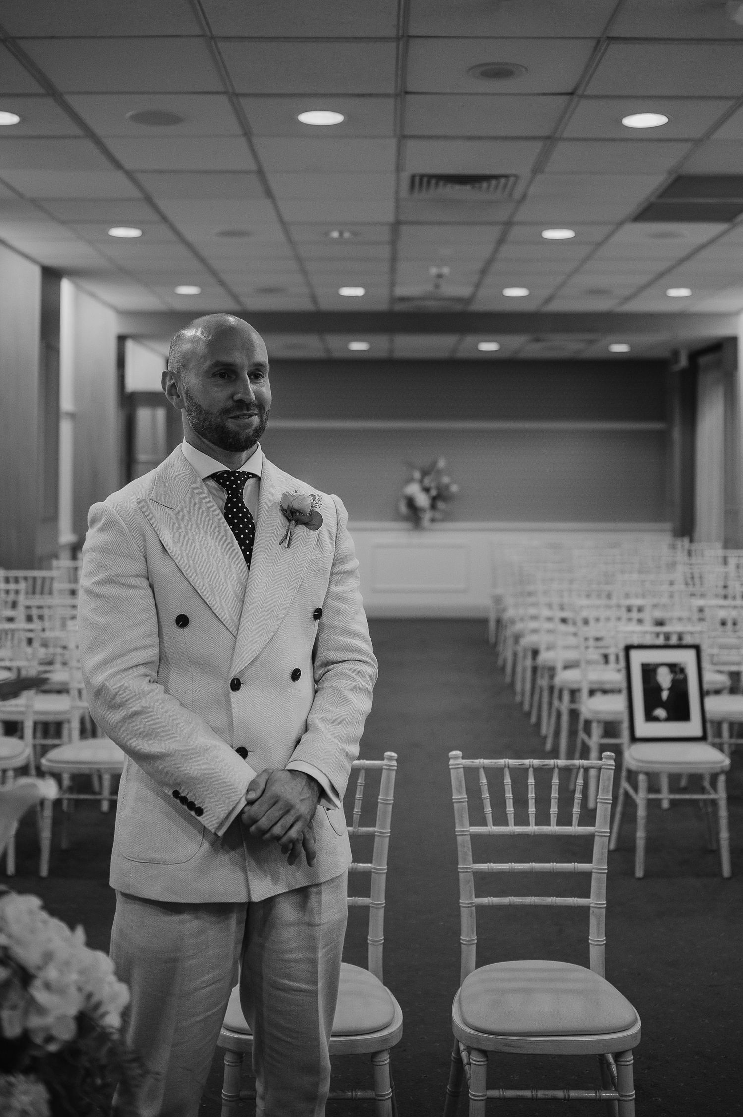 Wedding ceremony setup with white chiavari chairs and elegant decor in an indoor venue.