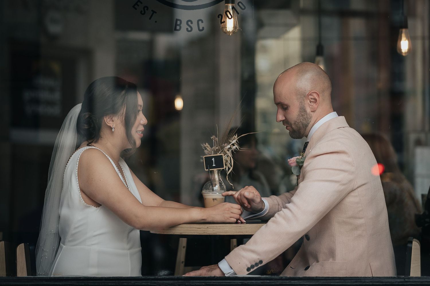 Couple sharing an intimate moment at a coffee shop table with coffee equipment.