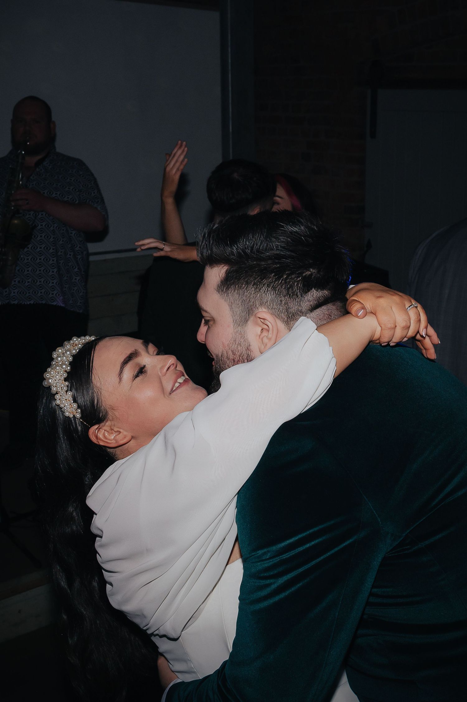Wedding couple dancing intimately in a dark reception venue.