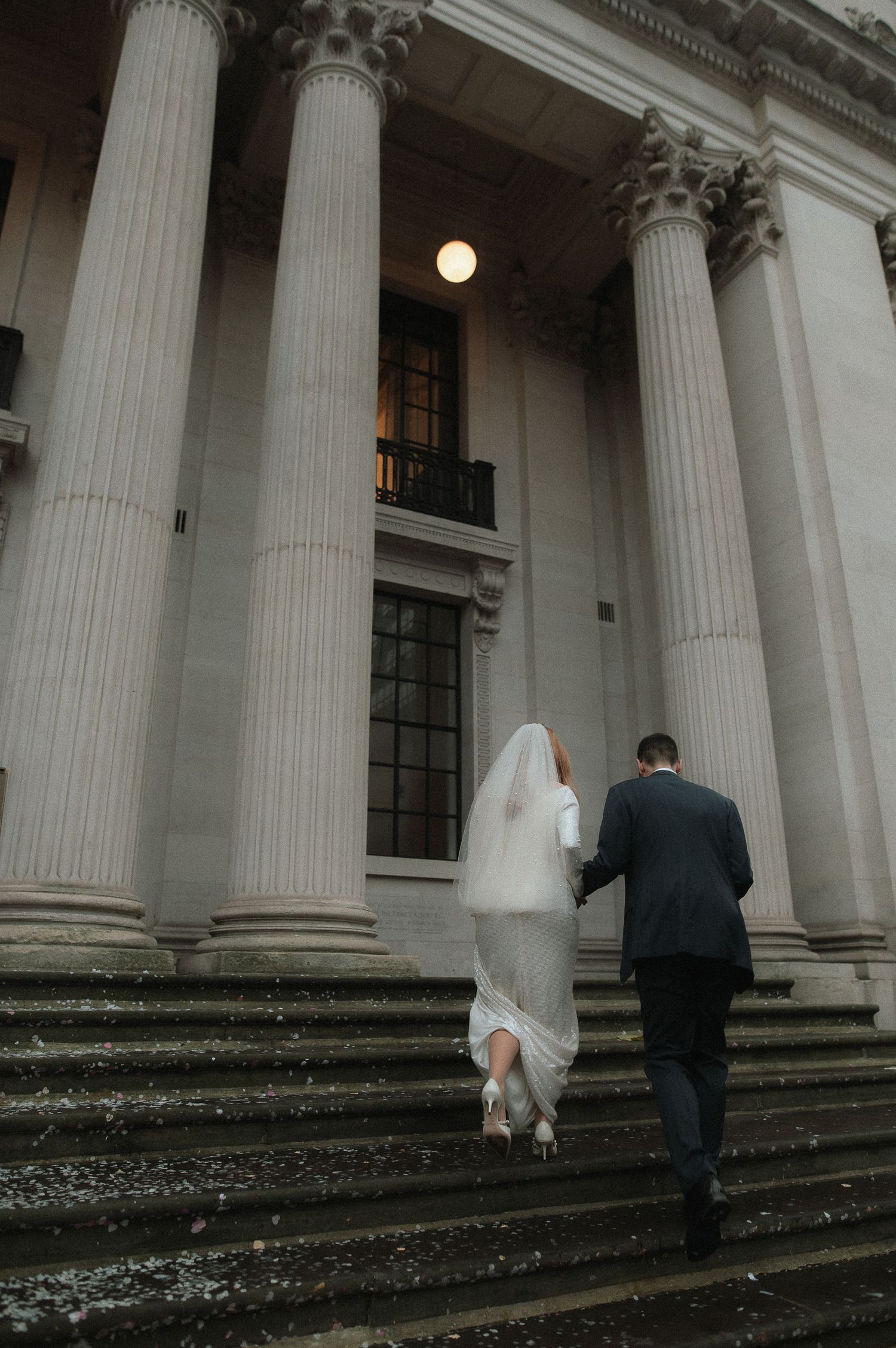 A wedding couple ascends stone steps between grand white columns in a series of progressive shots. London Wedding Photographer.