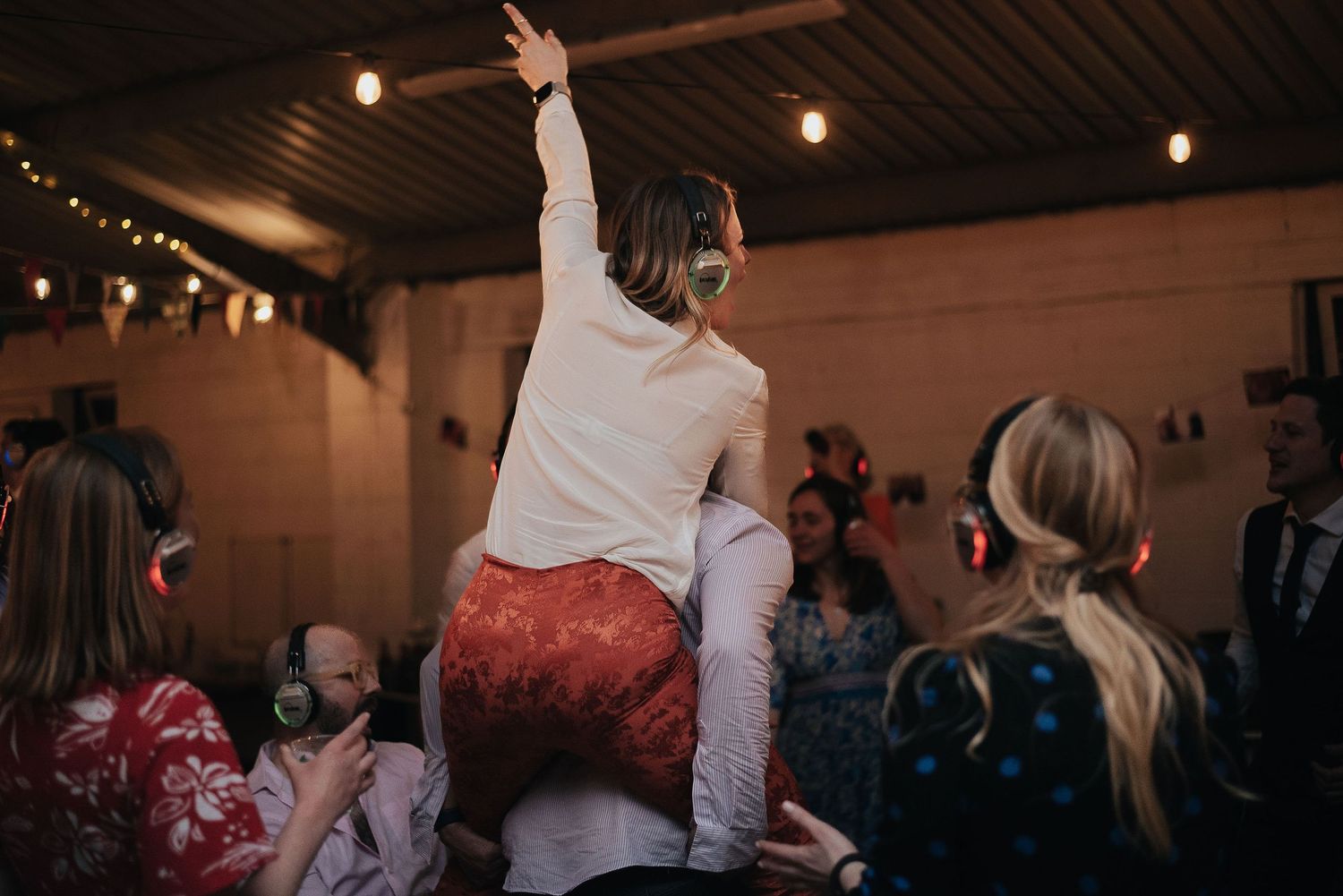 Wedding reception celebration with people dancing under indoor lighting.