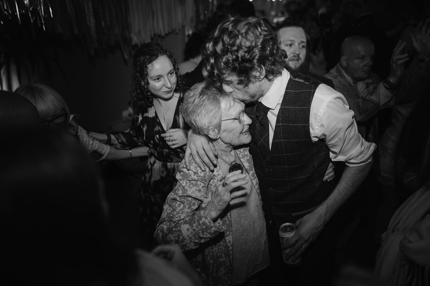 Black and white photo capturing joyful dancing and celebration at a crowded party.