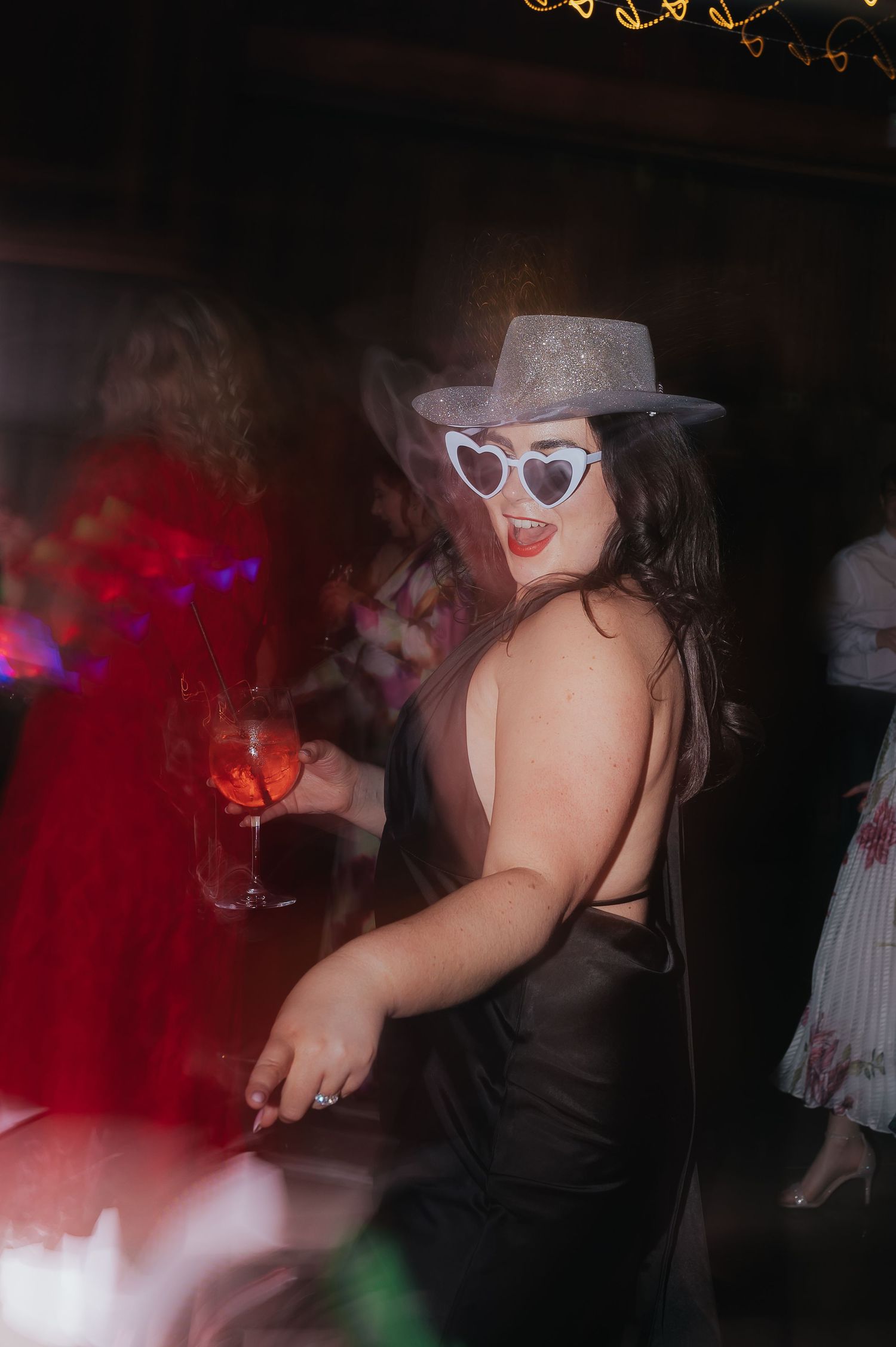 Party guest in sparkly hat and sunglasses enjoying the wedding reception dance floor.