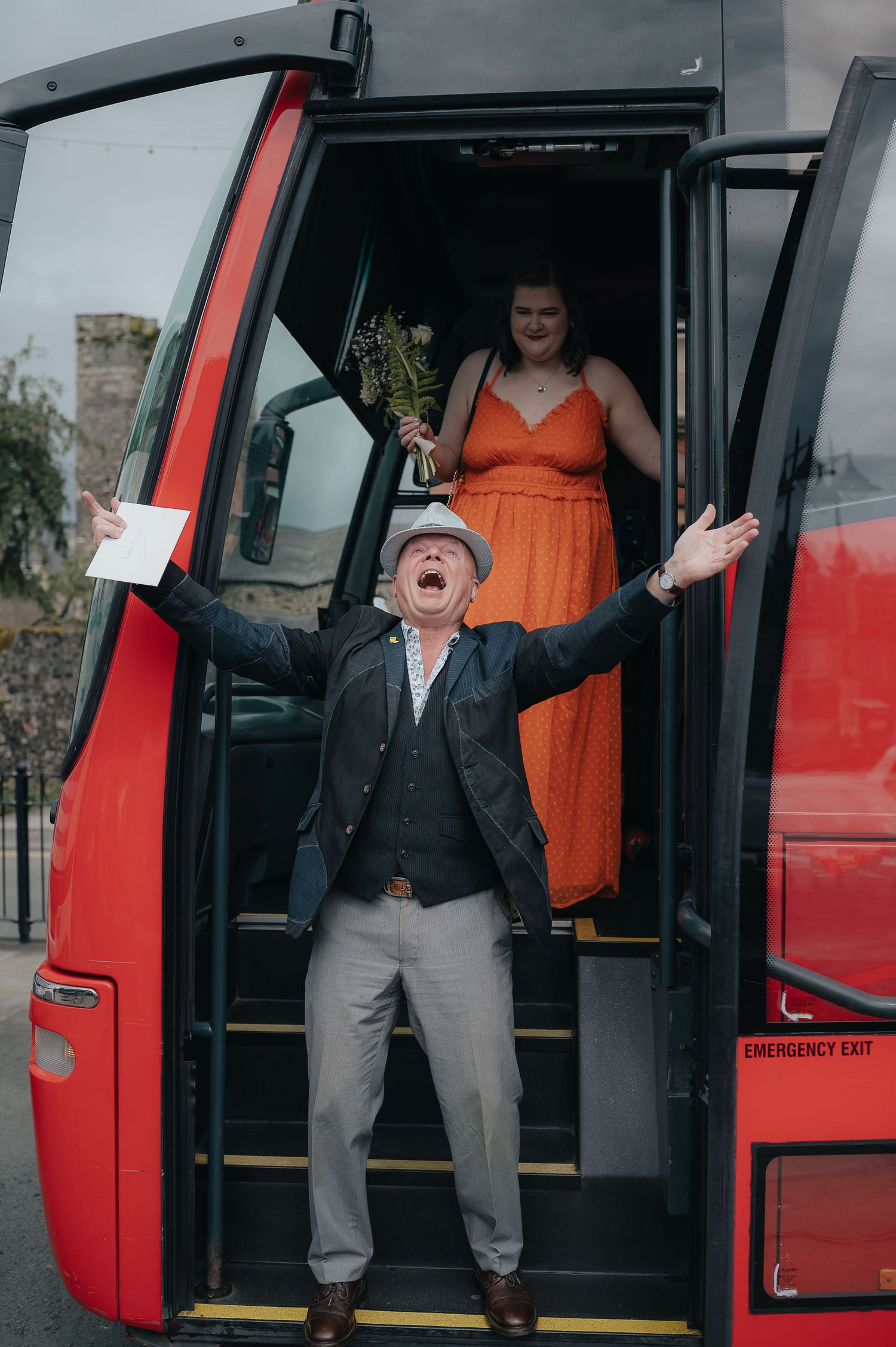 A joyful scene at a bus entrance with someone in orange and another person expressing excitement.