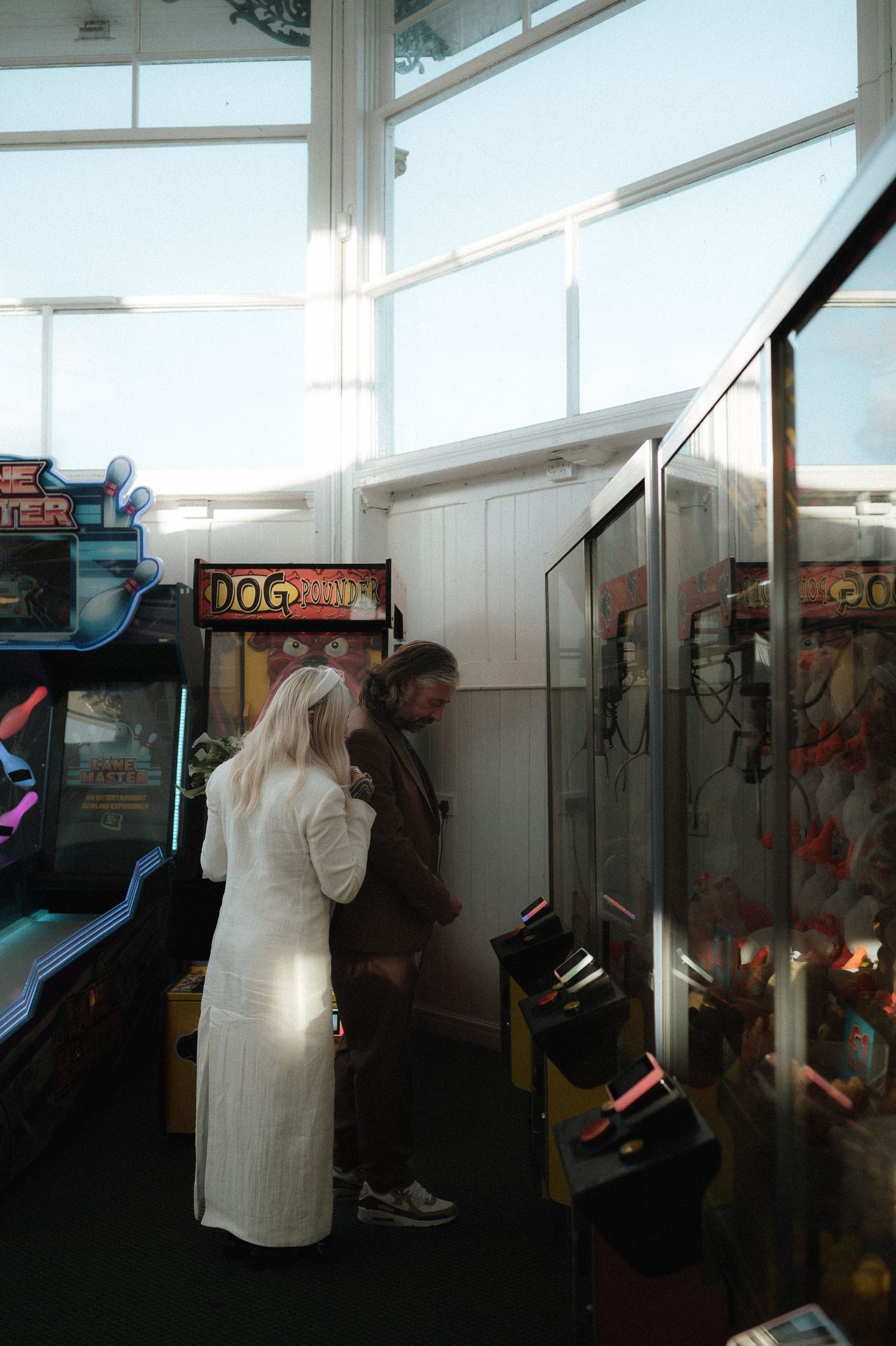 A series of arcade game machines lined up against a wall in a dimly lit gaming room.