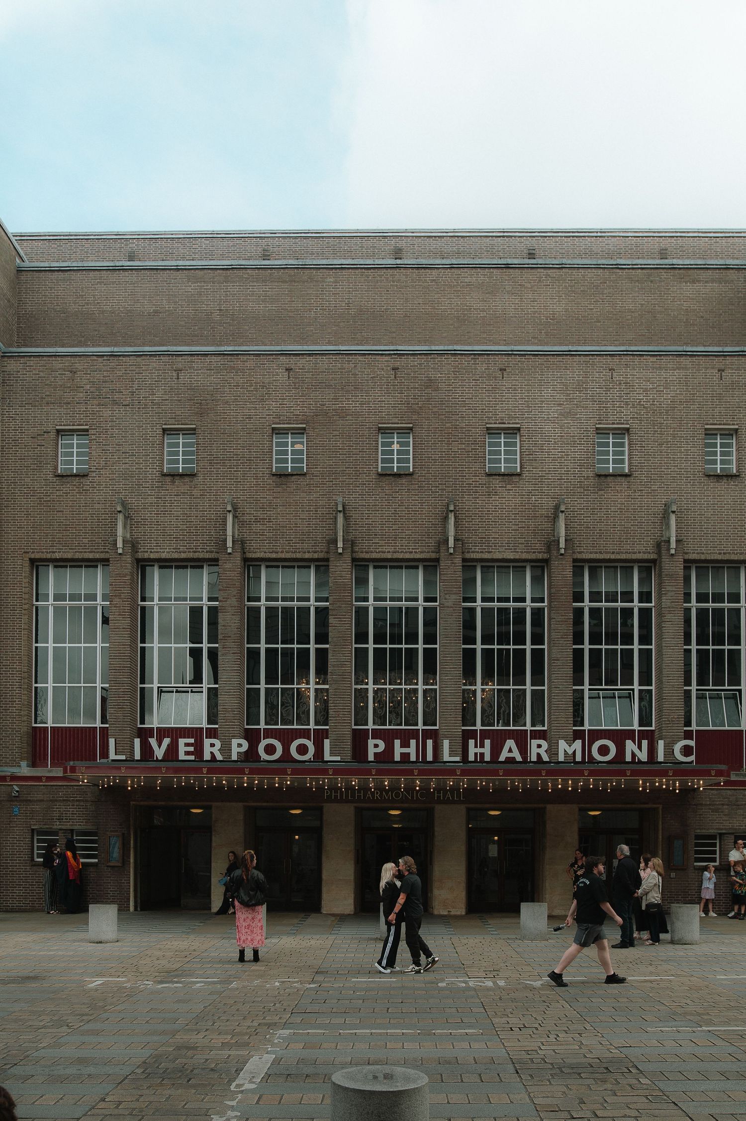 The exterior facade of Liverpool Philharmonic Hall with its modernist architecture and signage on a cloudy day.