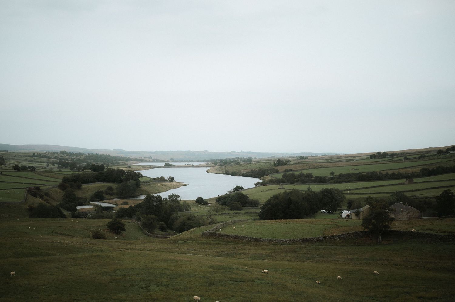 Rolling green hills and coastal cliffs meet the ocean in a dramatic landscape under cloudy skies. Blackton Grange Wedding