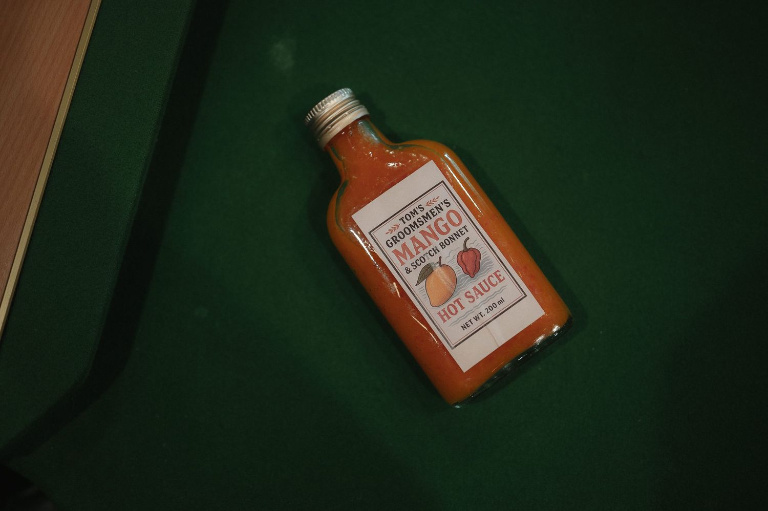 A bottle of orange-colored cocktail mixer on a dark green background.